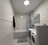 Koupelna v 2-pokojovém bytě se sprchovým koutem, vanou a pračkou.