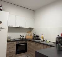 Kuchyně v 2-pokojovém bytě s podlahou s dřevěným dekorem a bílými skříňkami.