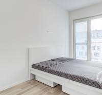 Světlá ložnice s postelí a podlahou s dřevěným dekorem v 2-pokojovém bytě.