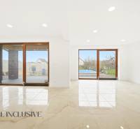 Obývací pokoj v rodinném domě s velkými skleněnými dveřmi a výhledem na dvůr.