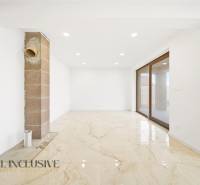 Prostorná místnost rodinného domu s velkými okny a světlou podlahou.