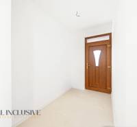 Vstupní chodba rodinného domu s bílými stěnami a tmavými dveřmi.