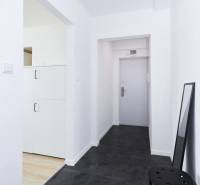 Chodba s tmavou podlahou a bílými stěnami v 2-pokojovém bytě.