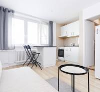 Kuchyně v 2-pokojovém bytě s bílým nábytkem a podlahou s dřevěným dekorem.