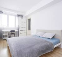 Světlá ložnice v 2-pokojovém bytě s psacím stolem a podlahou s dřevěným dekorem.