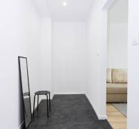 Úzká chodba v 2-pokojovém bytě s černou podlahou a zrcadlem.