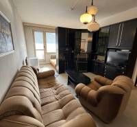 Obývací pokoj v 2-pokojovém bytě s pohodlnou pohovkou a skříňovou sestavou.