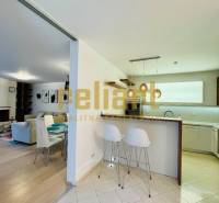 Kuchyně a obývací pokoj v rodinném domě s barovým pultem a židlemi.