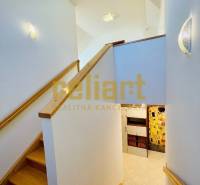 Interiér rodinného domu se schodištěm a podlahou s dřevěným dekorem.