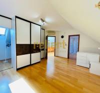 Podkrovní pokoj s podlahou s dřevěným dekorem a vestavěnou skříní v rodinném domě.