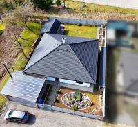 Rodinný dům v Pružině s velkou střechou, zahradou a garáží s přístřeškem.