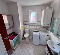Koupelna obsahuje pračku, skříňky, WC a umyvadlo, vhodná pro 1-pokojový byt.
