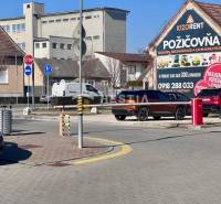 Ulice ve městě s auty, cyklostezkou a budovou Půjčovny nářadí, 1-pokojový byt nezmíněn.