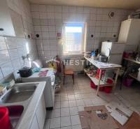 Kuchyně s podlahou z dlaždic, sporákem a nádobím na poličce, gastro prostory.