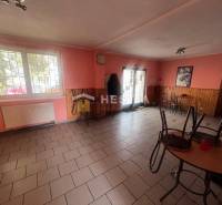 Gastro prostory s cihlovou podlahou, dřevěným dekorem na stěnách a stoly.