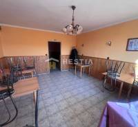 Oranžově laděné gastro prostory s kachličkovou podlahou, stoly s obrácenými židlemi.