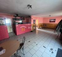 Interiér gastro prostoru s červeným cihlovým pultem a růžovými stěnami.