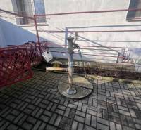 Vodní pumpa na betonové dlažbě u budovy v Gastroprostorech v Senici.