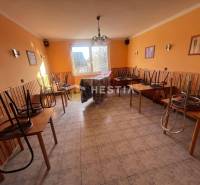 Gastro prostory s dlažbou, židle na stolech, oranžové stěny a okno do dvora.