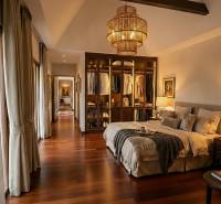 Stylová ložnice ve vile s podlahou s dřevěným dekorem a otevřenou šatnou.