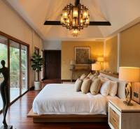 Luxusní ložnice ve vile s podlahou s dřevěným dekorem a velkými okny.