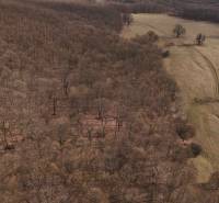 Krajina v Príbelsciach s lesními a zemědělskými pozemky přecházejícími do otevřených luk.