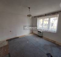 Pokoj s kobercem, bílými stěnami a velkým oknem, vhodný k rekonstrukci; Pozemky - bydlení.