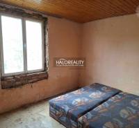 Pokoj s postelí, neopracovanými stěnami a dřevěným stropem, kategorie Pozemky - bydlení.