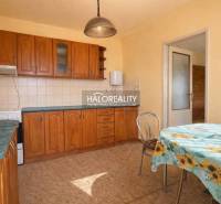 Kuchyně v rodinném domě s vestavěnými skříňkami a stolem s květinovým ubrusem.