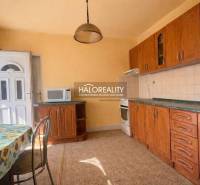 Kuchyně rodinného domu s dřevěným dekorem a slunečním stěnovým dekorem.