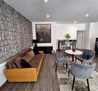 Obývací pokoj v rodinném domě s pohodlnou sedačkou a jídelními židlemi.