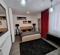 Ložnice v rodinném domě se zrcadlem, červenými závěsy a dekoracemi na stěně.