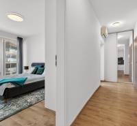 Ložnice s velkým oknem a chodba s podlahou s dřevěným dekorem v 2-pokojovém bytě.