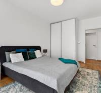 Ložnice v 2-pokojovém bytě s postelí, nočním stolkem a skříní.