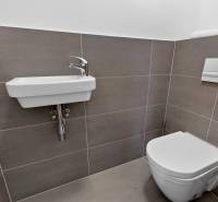 Koupelna s umyvadlem a toaleta v 2-pokojovém bytě s jednoduchými obklady.