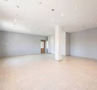 Obchodní prostory s bílými stěnami, keramickou podlahou a bodovým osvětlením.