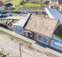 Obchodní prostory v Okoči s tradiční střechou, chodníkem a zahradou.