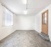 Bílé stěny, betonová podlaha, dřevěné dveře a záclona v obchodních prostorách.