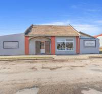 Obchodní prostory ve městě Okoč s výkladními okny a šikmou střechou.