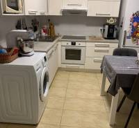 Kuchyně ve 2-pokojovém bytě s bílými skříňkami a keramickou podlahou.