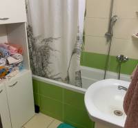 Koupelna s vanou a barevnými obklady v 2pokojovém bytě.