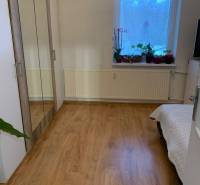 Pokoj v 2-pokojovém bytě s podlahou s dřevěným dekorem a skříní se zrcadlem.