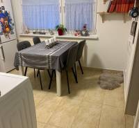 Jídelní kout v 2-pokojovém bytě s bílým stolem a šedými židlemi.