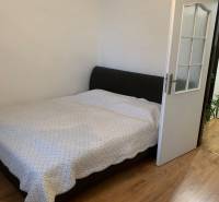 Ložnice v 2pokojovém bytě s podlahou s dřevěným dekorem a velkou postelí.