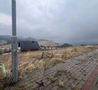 Pohled na pozemky - bydlení ve Staré Ľubovni s viditelným chodníkem a domem.