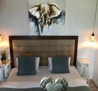 Ložnice se stylovým osvětlením a obrazem slona v 2pokojovém bytě.