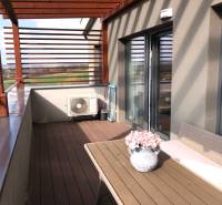 Terasa 2-pokojového bytu s výhledem na okolí a květinovou dekorací.