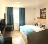 Světlý pokoj ve 2-pokojovém bytě s modrými závěsy a podlahou s dřevěným dekorem.