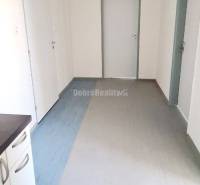 Chodba v kanceláři se světlými stěnami, dveřmi a podlahou s dřevěným dekorem.