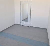 Malá kancelář s modrou podlahou, zrcadlem a klimatizací.